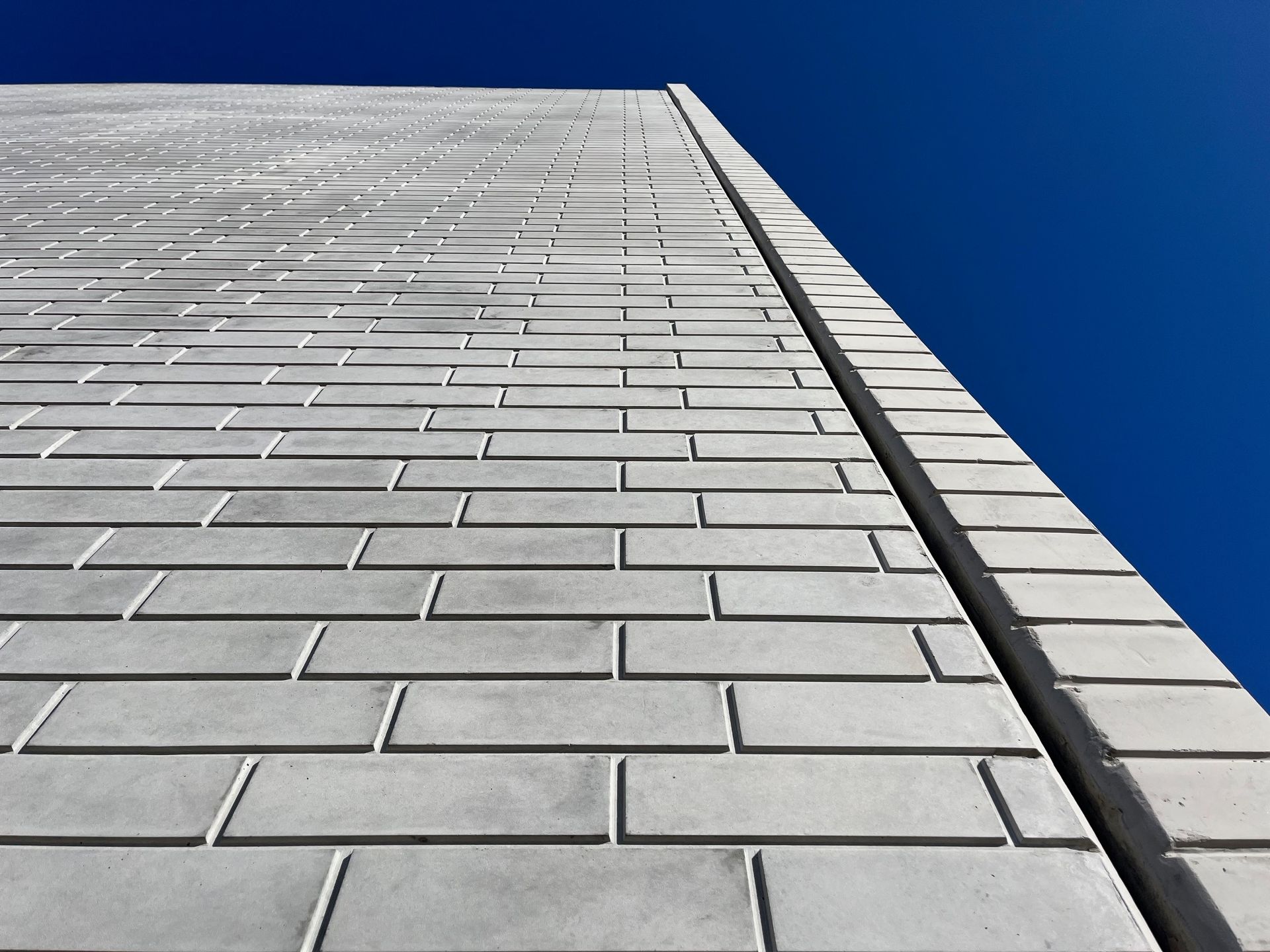 Gray brick wall against a bright blue sky, viewed from a low angle.