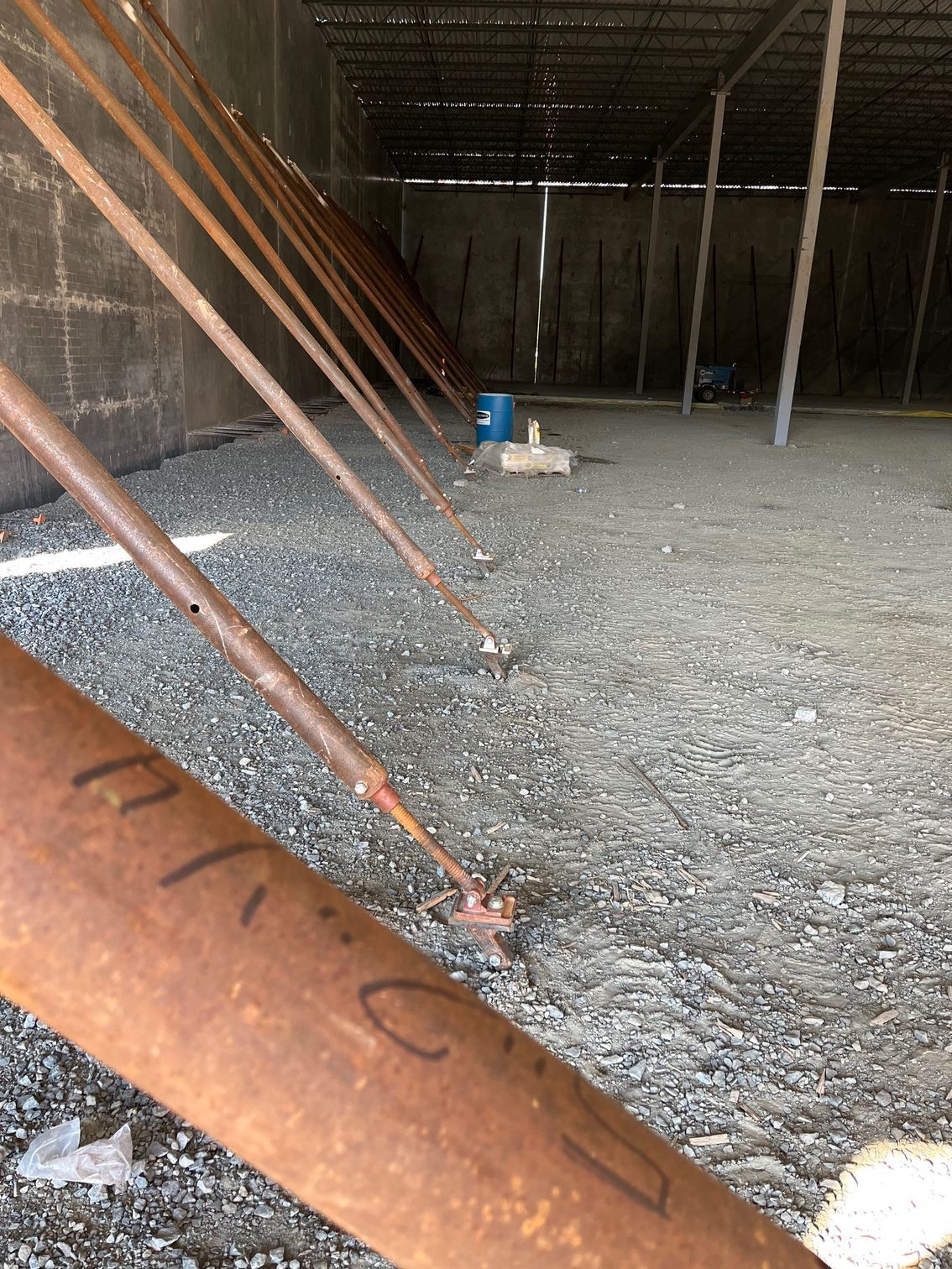 Metal beams braced against a dark, enclosed structure; ground covered in gravel.