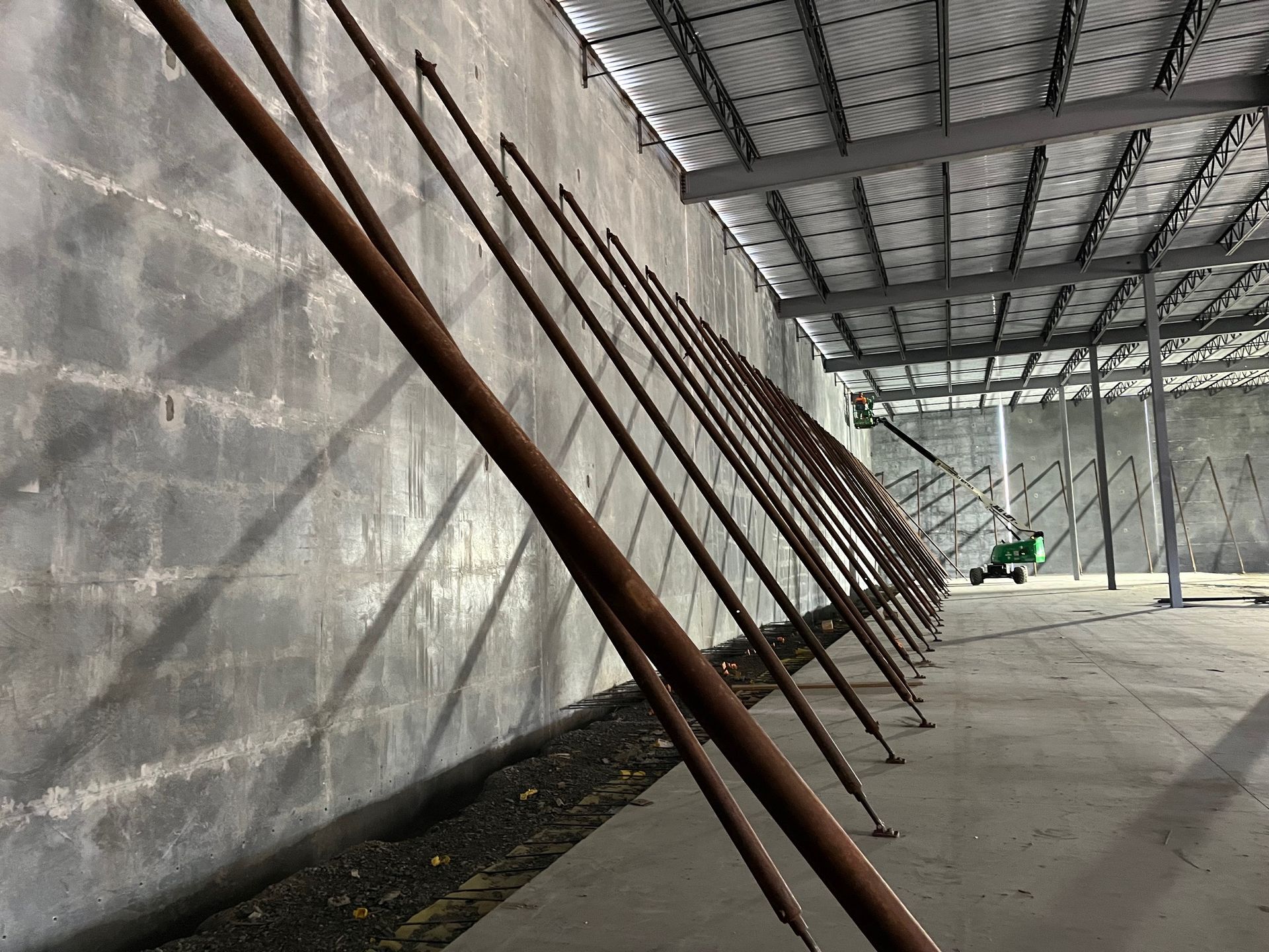 Long metal supports angled against a concrete wall inside a building under construction.