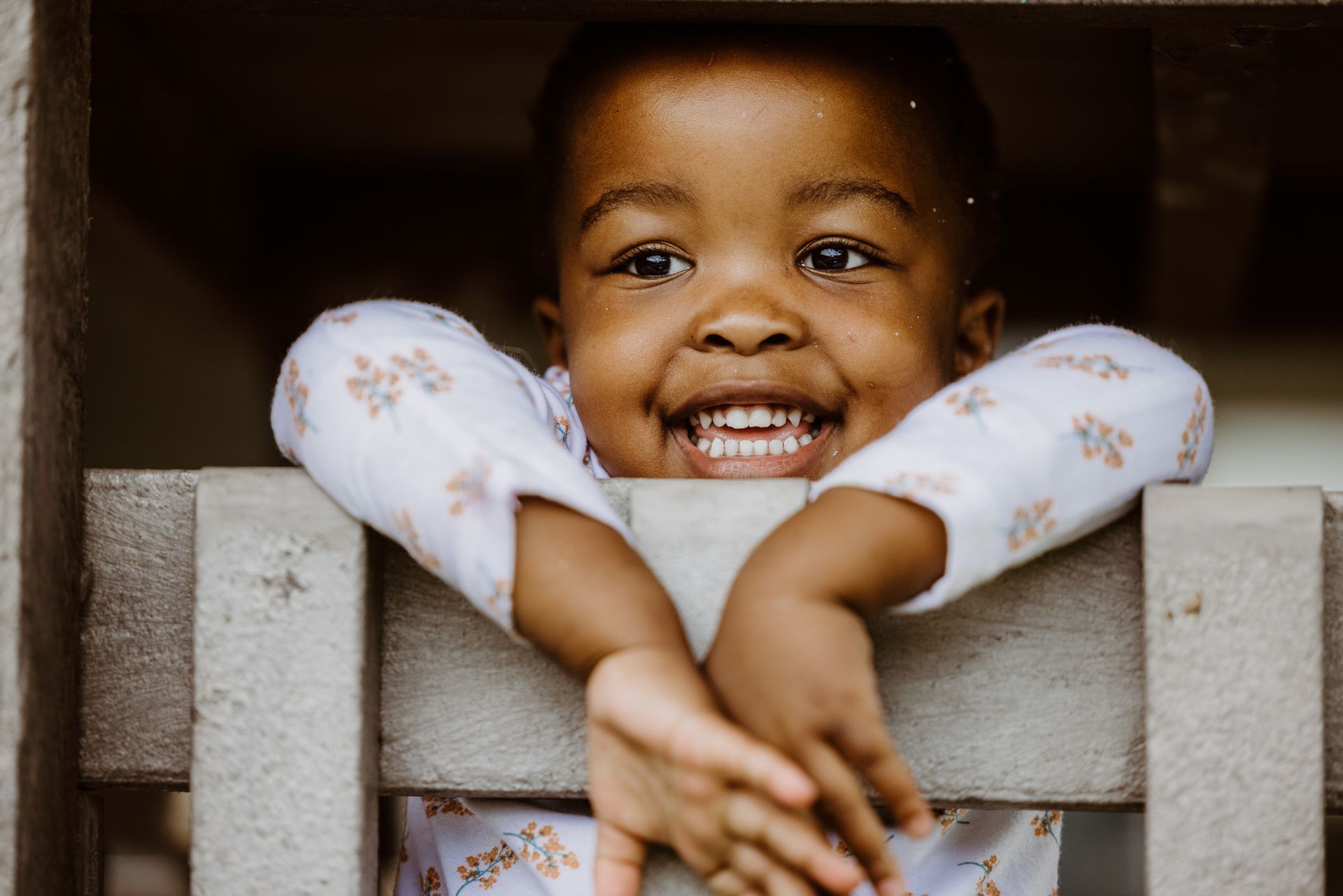 A little boy is smiling while looking out of a window.
