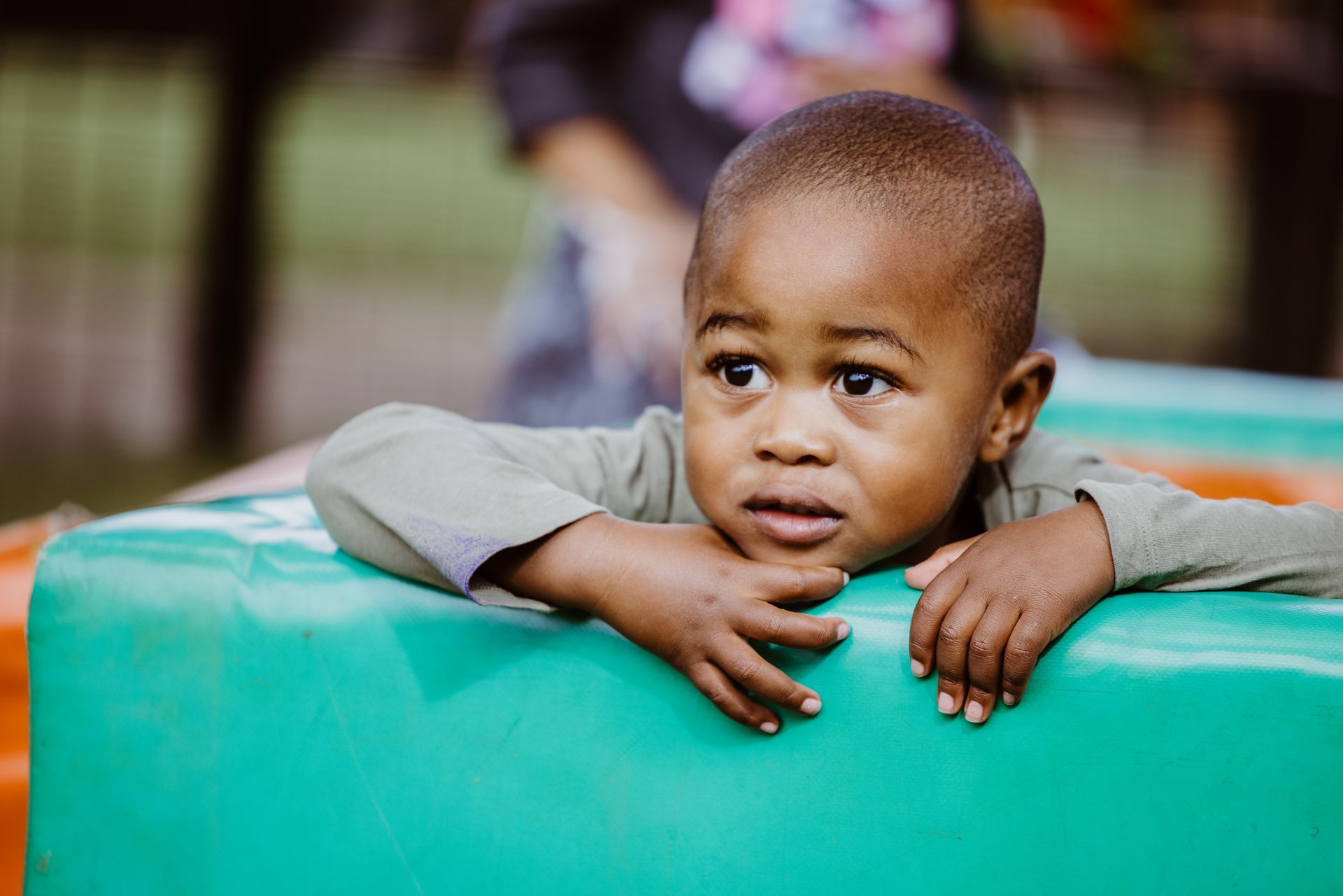 A young boy is laying on a green foam block.