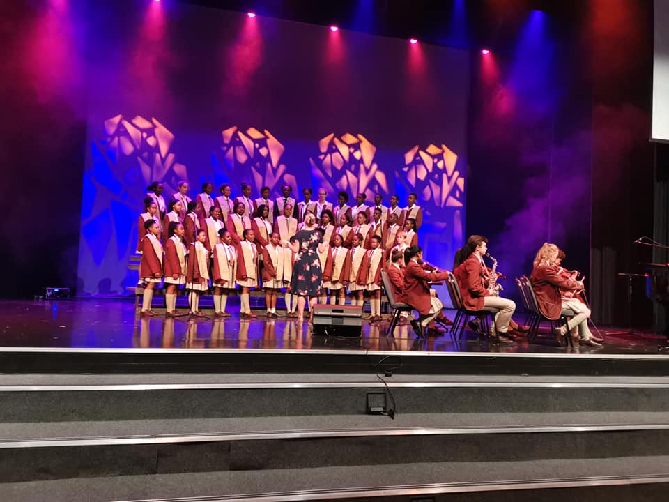 A choir and a band are performing on a stage.