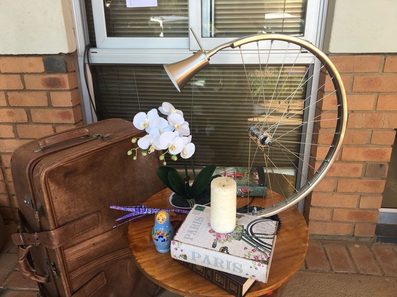 A table with a lamp a suitcase a book and a candle on it