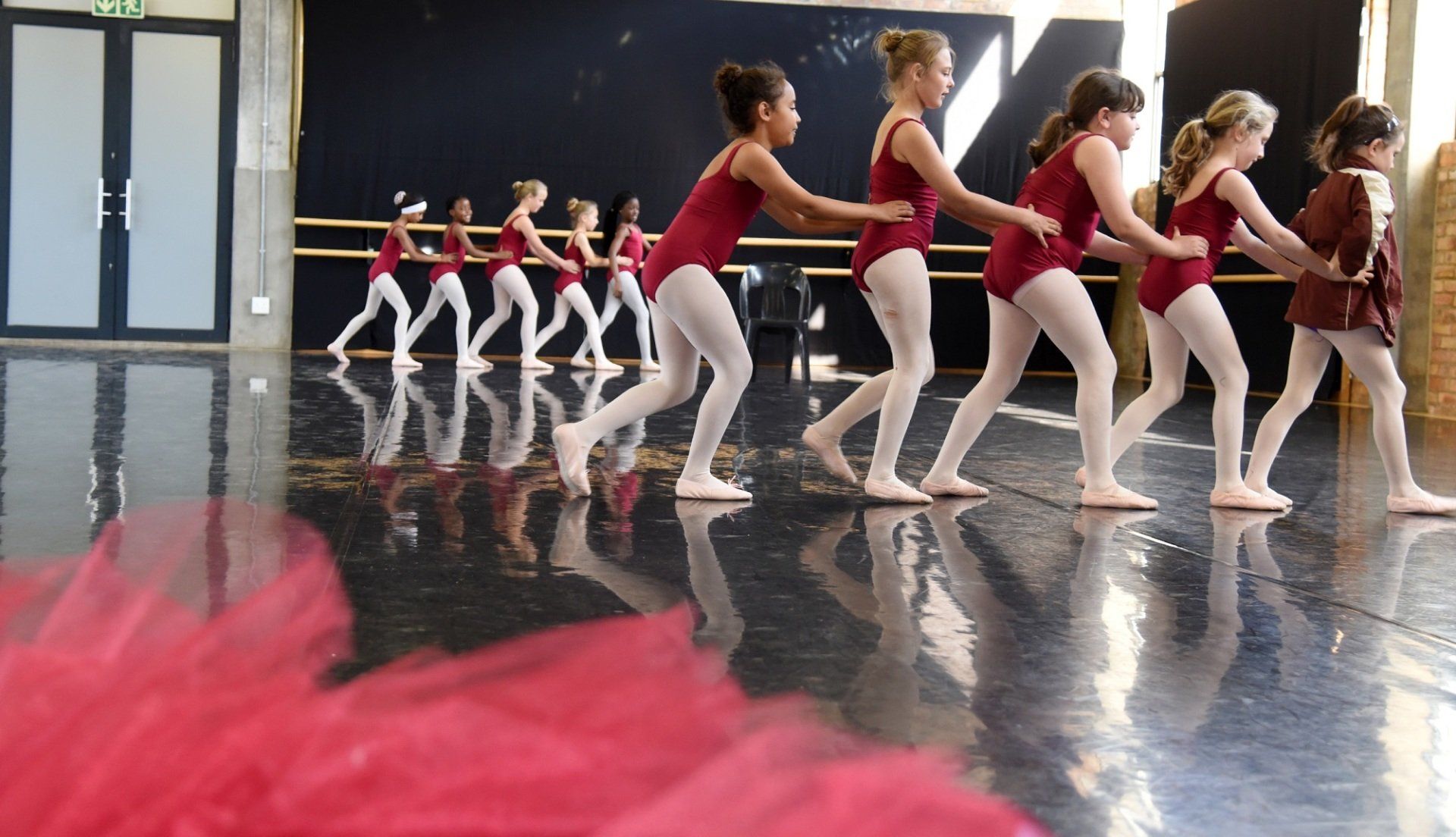 A group of young girls are dancing in a dance studio