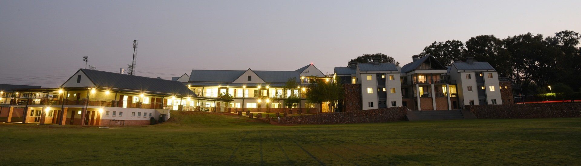 A row of houses are lit up at night in a field.