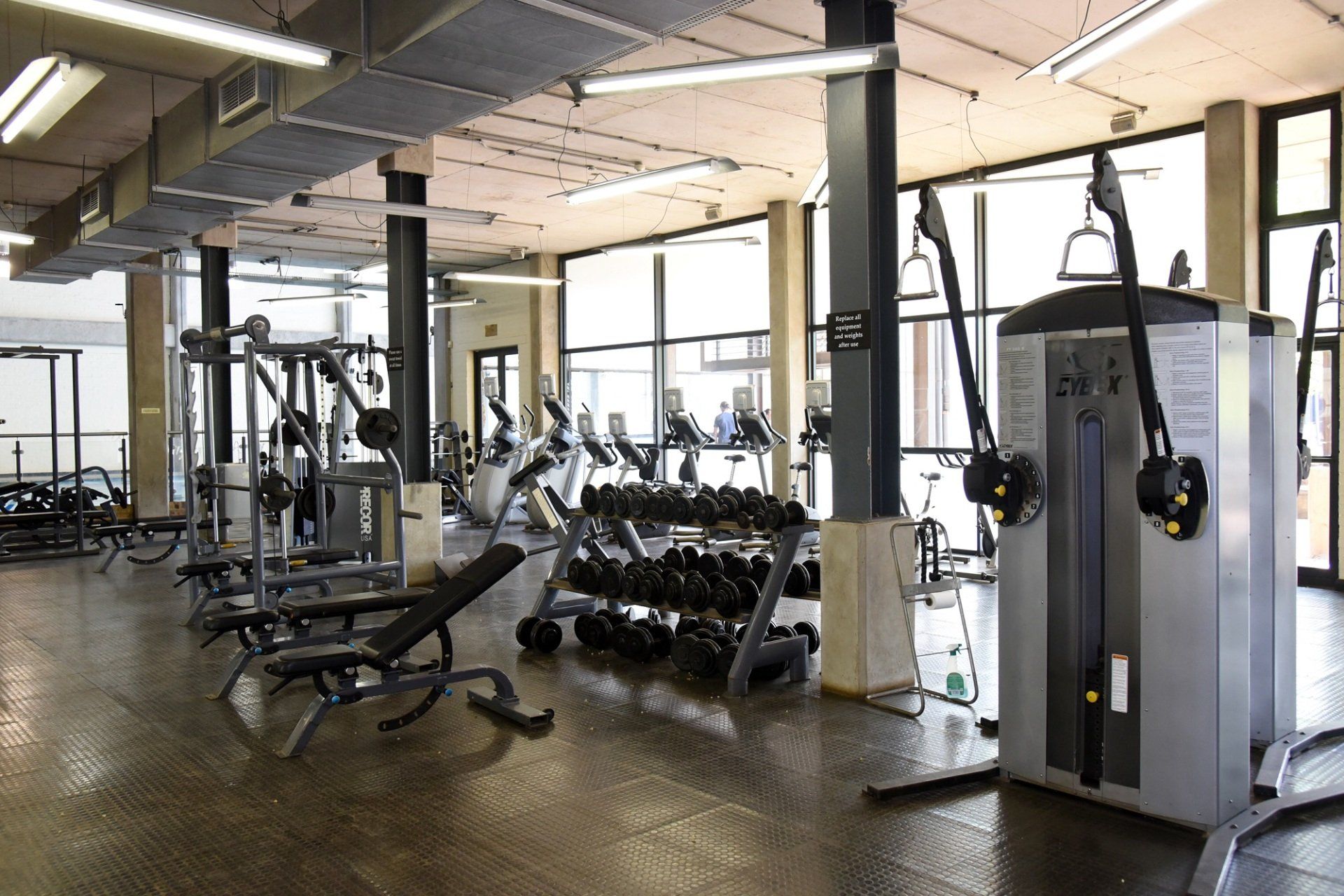 A gym with a lot of dumbbells and exercise equipment