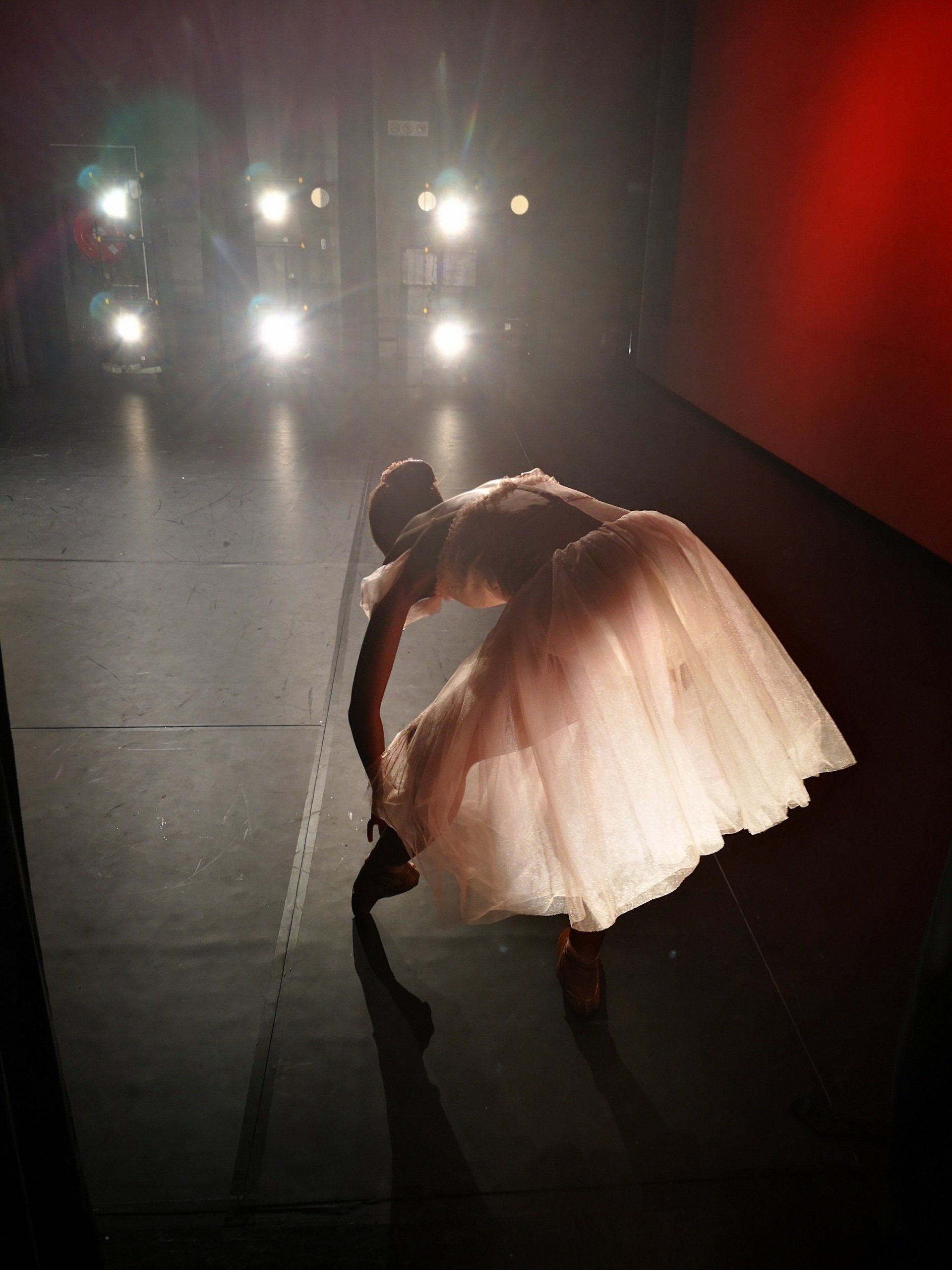 A woman in a white dress is bending over on a stage