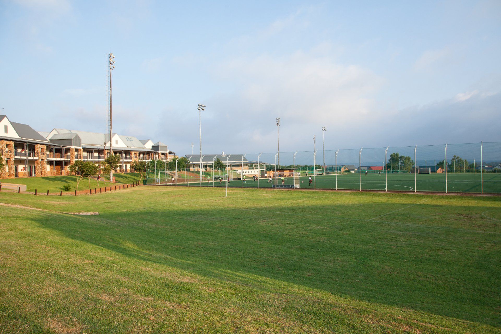 A soccer field with a fence and houses in the background