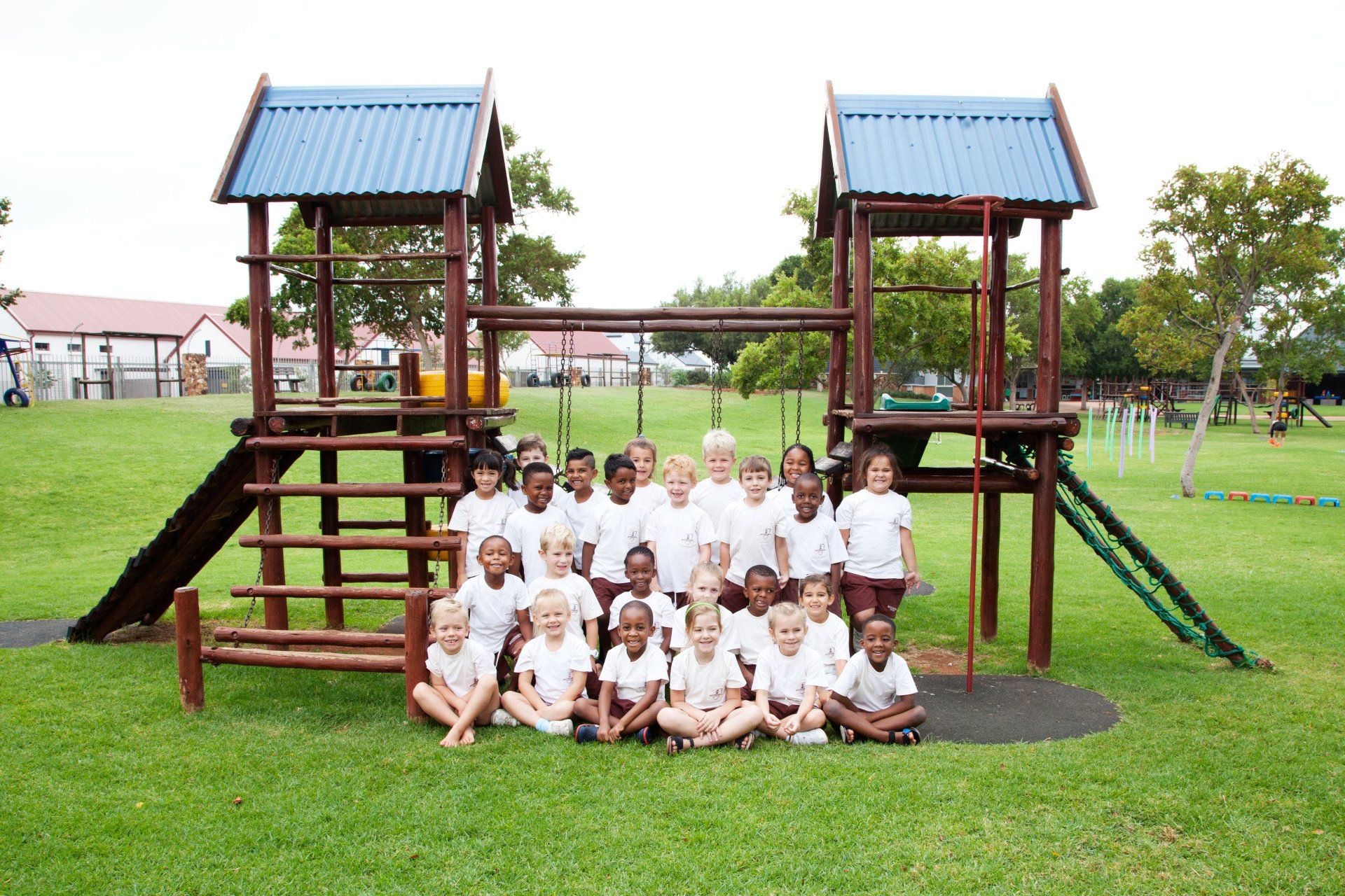 A group of children are posing for a picture in front of a playground.