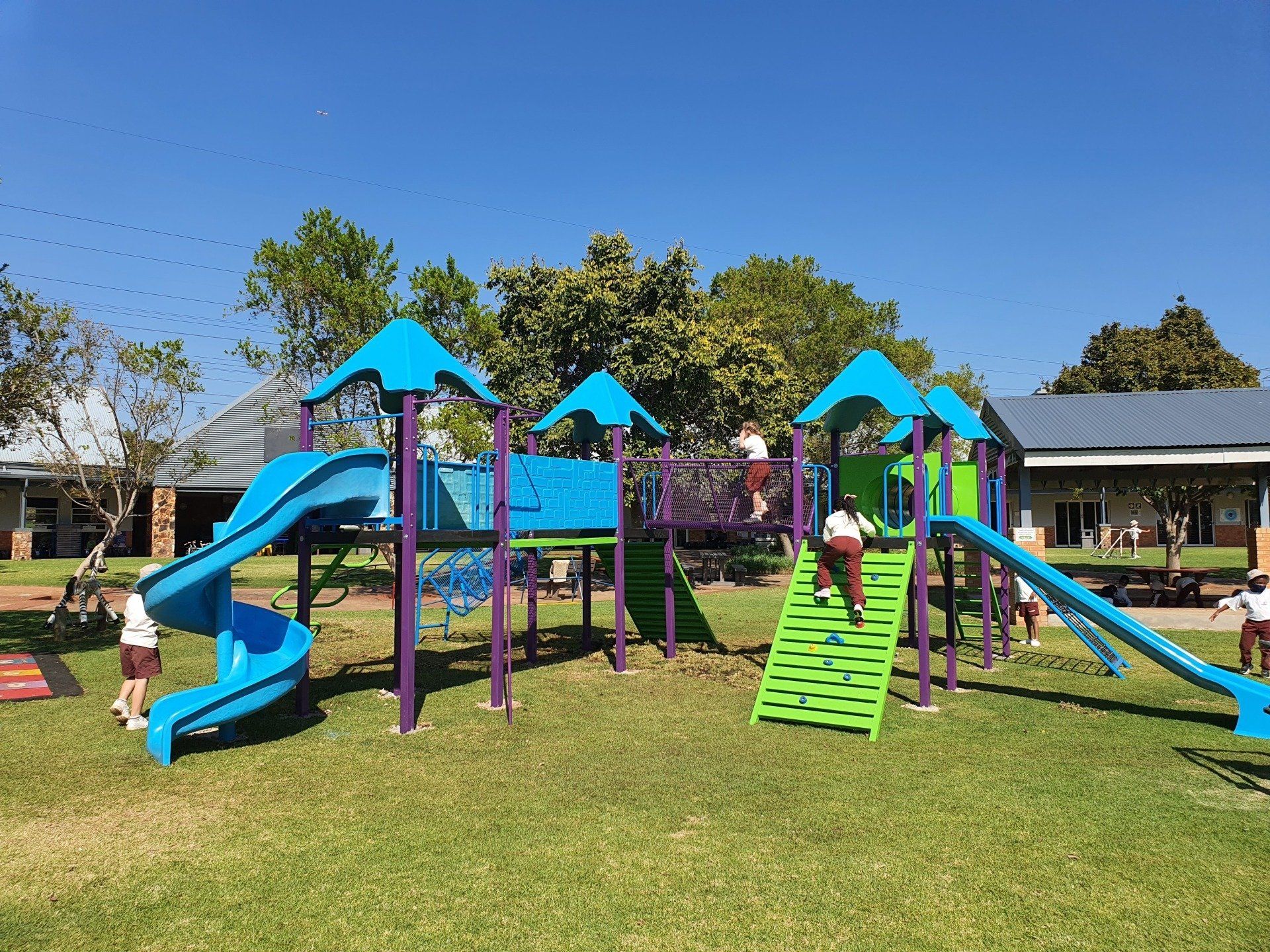 A blue and purple playground with a slide and stairs in a park.