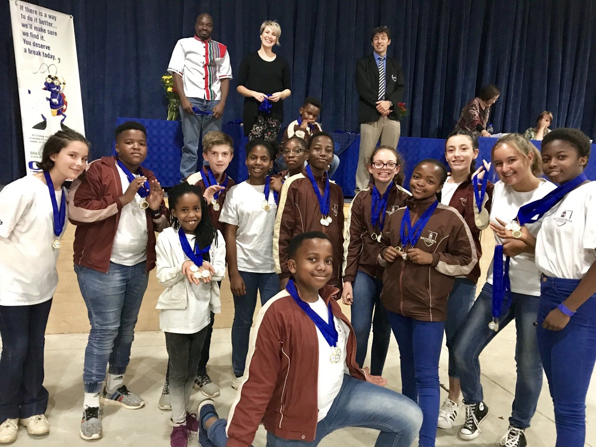 A group of young people wearing medals are posing for a picture.
