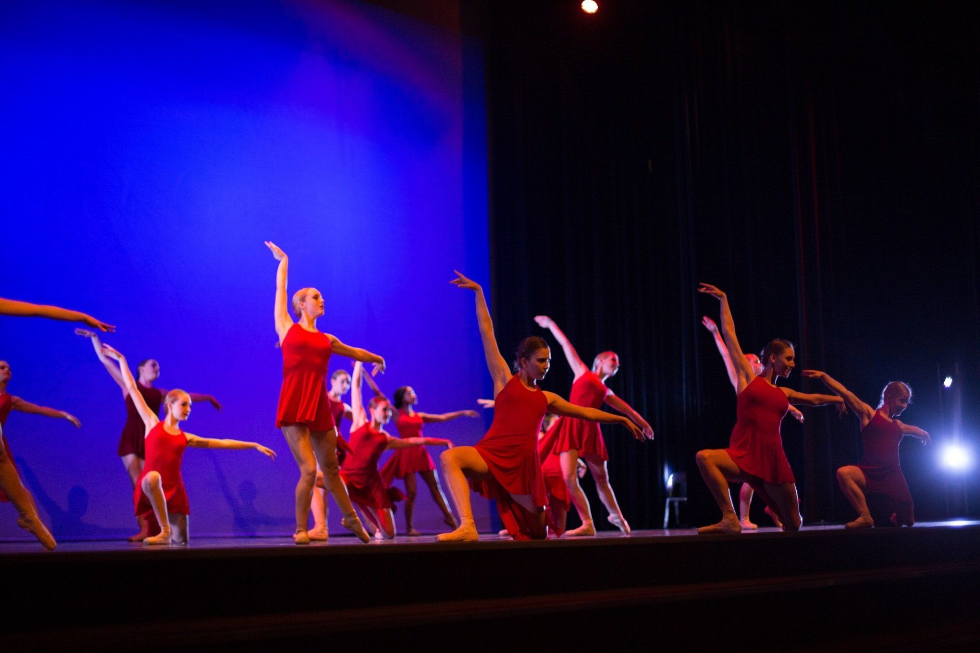 A group of dancers in red dresses are performing on a stage.