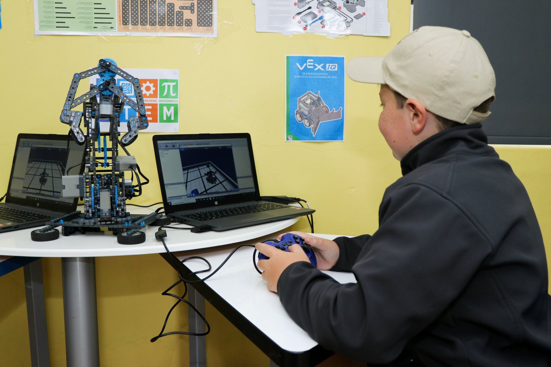 A boy is sitting at a desk playing a video game on a laptop.