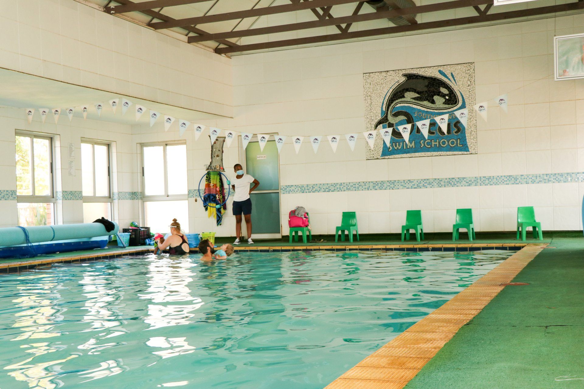 A large indoor swimming pool with a dolphin on the wall