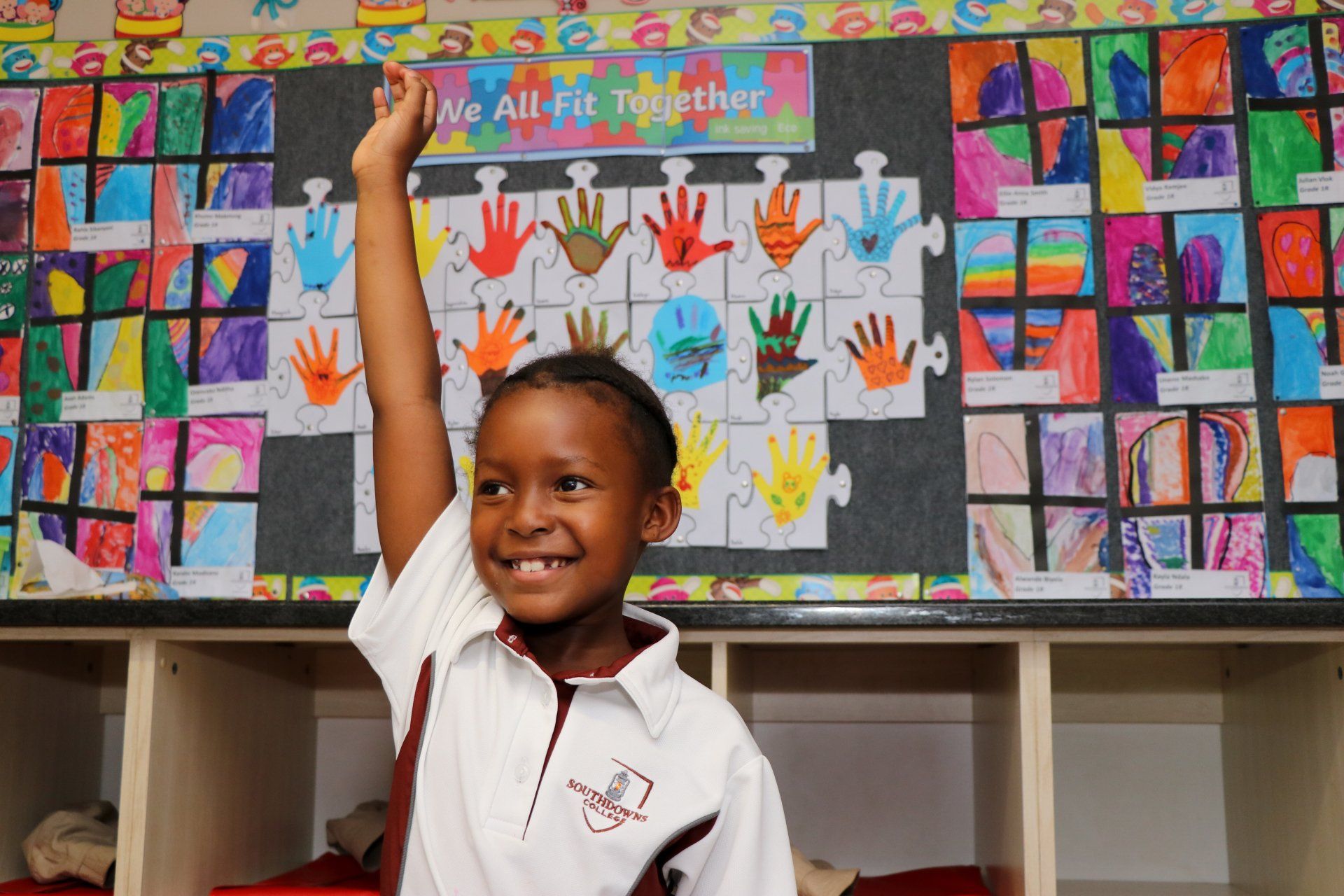 A young boy raising his hand in front of a sign that says