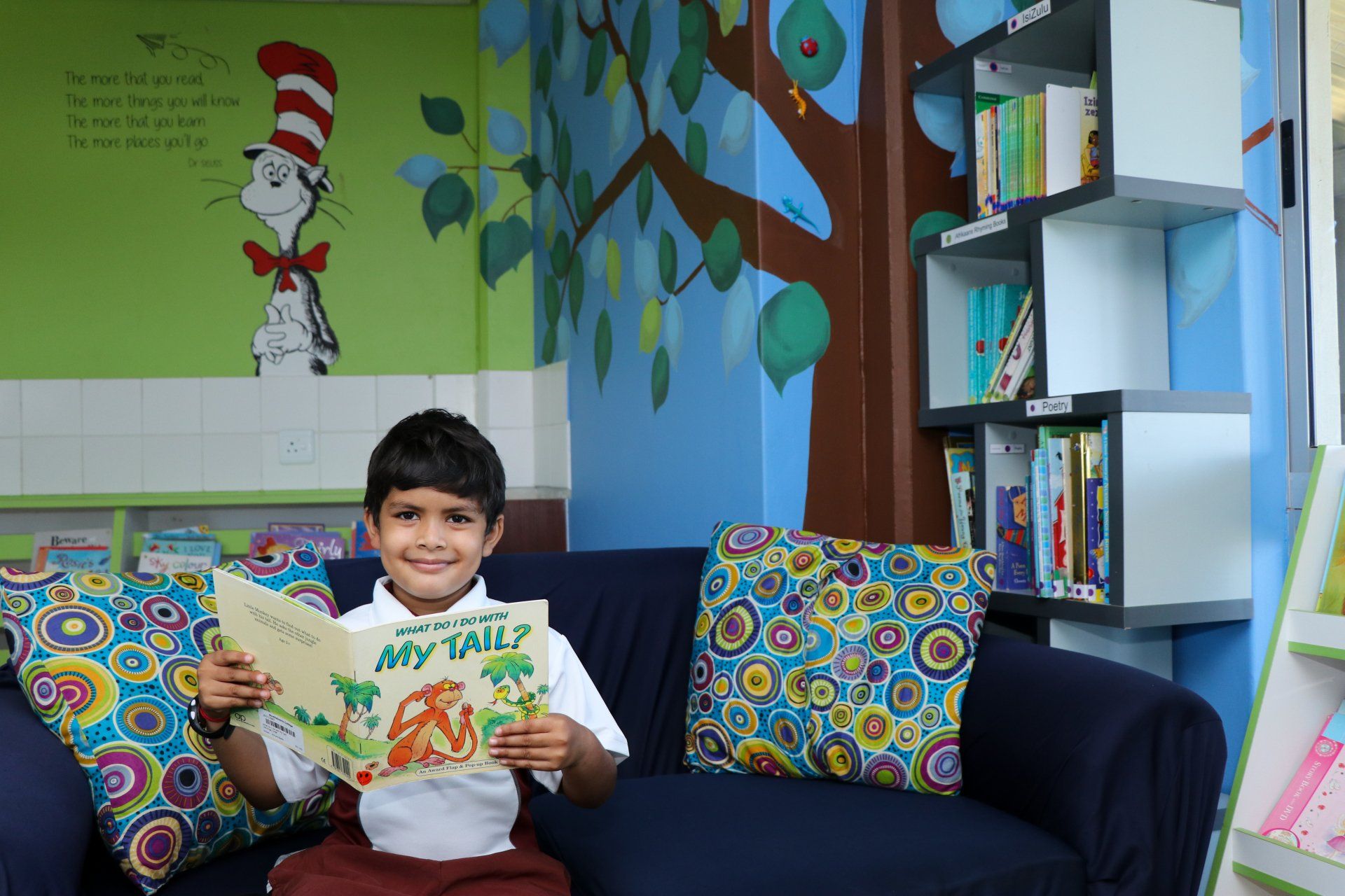 A young boy is sitting on a couch reading a book.