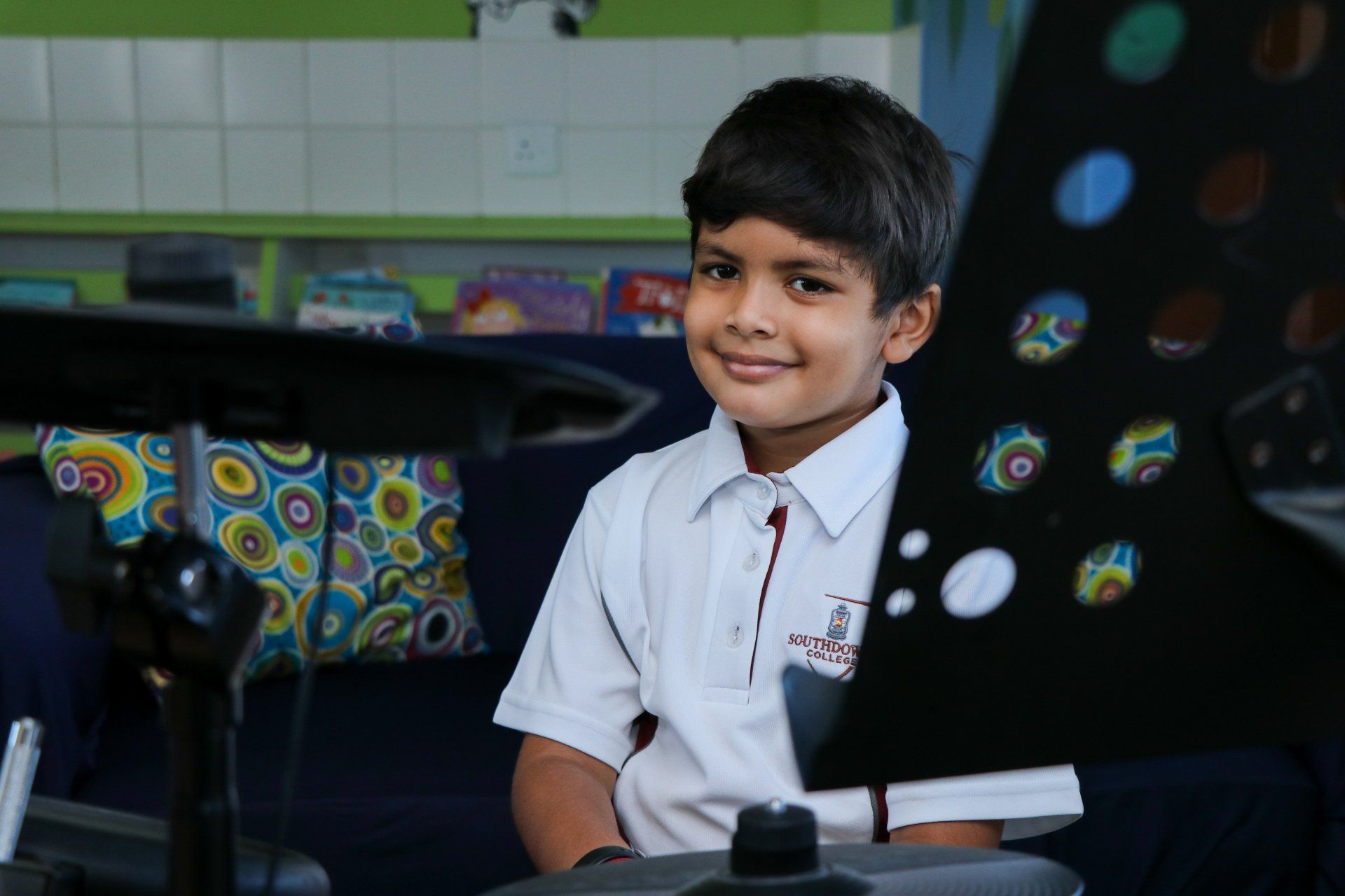 A young boy is sitting in front of a microscope in a classroom.