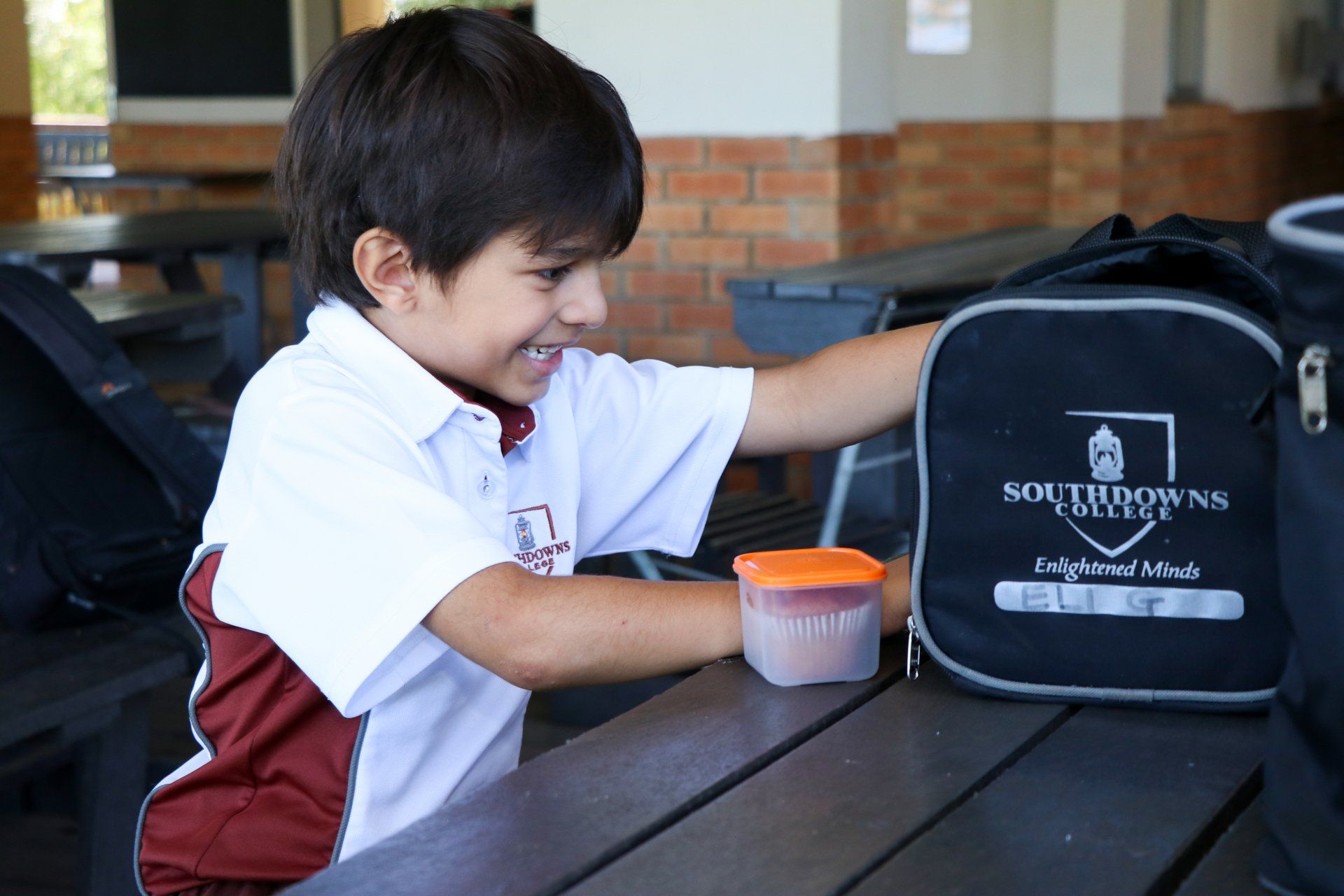 A young boy is putting something in a southdowns lunch bag