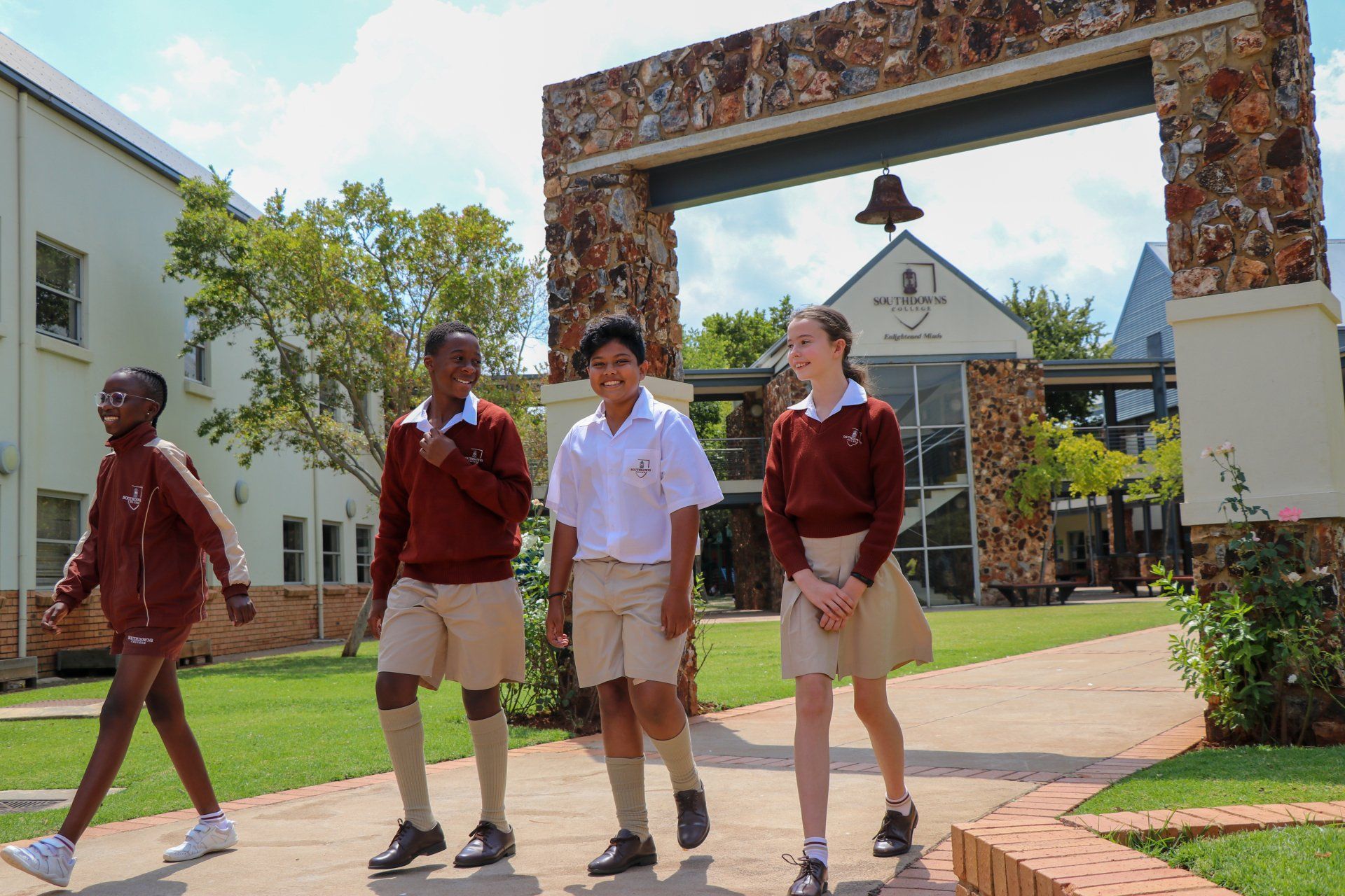 A group of children are walking in front of a school building.