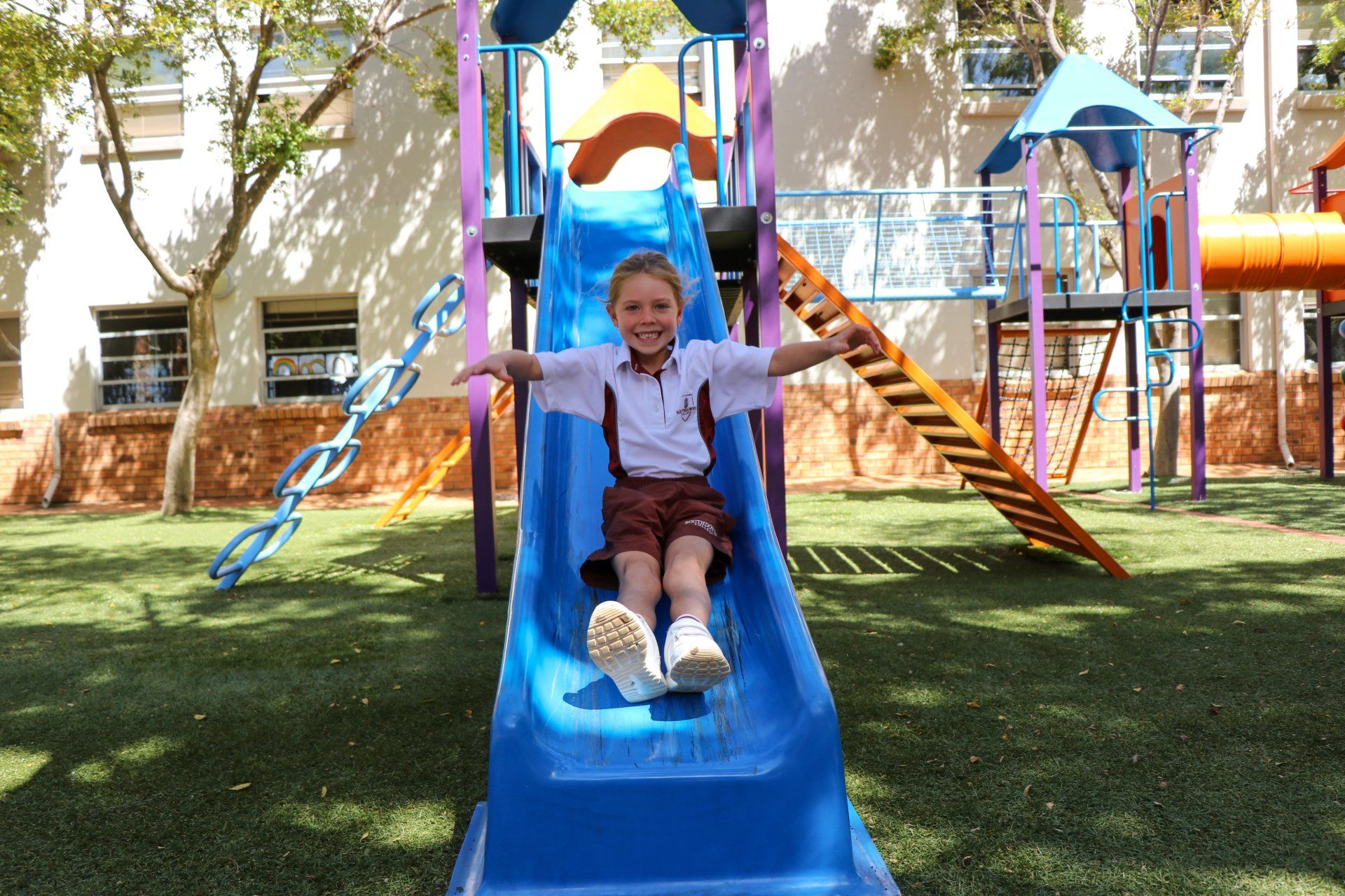 A young boy is sitting on a slide in a playground