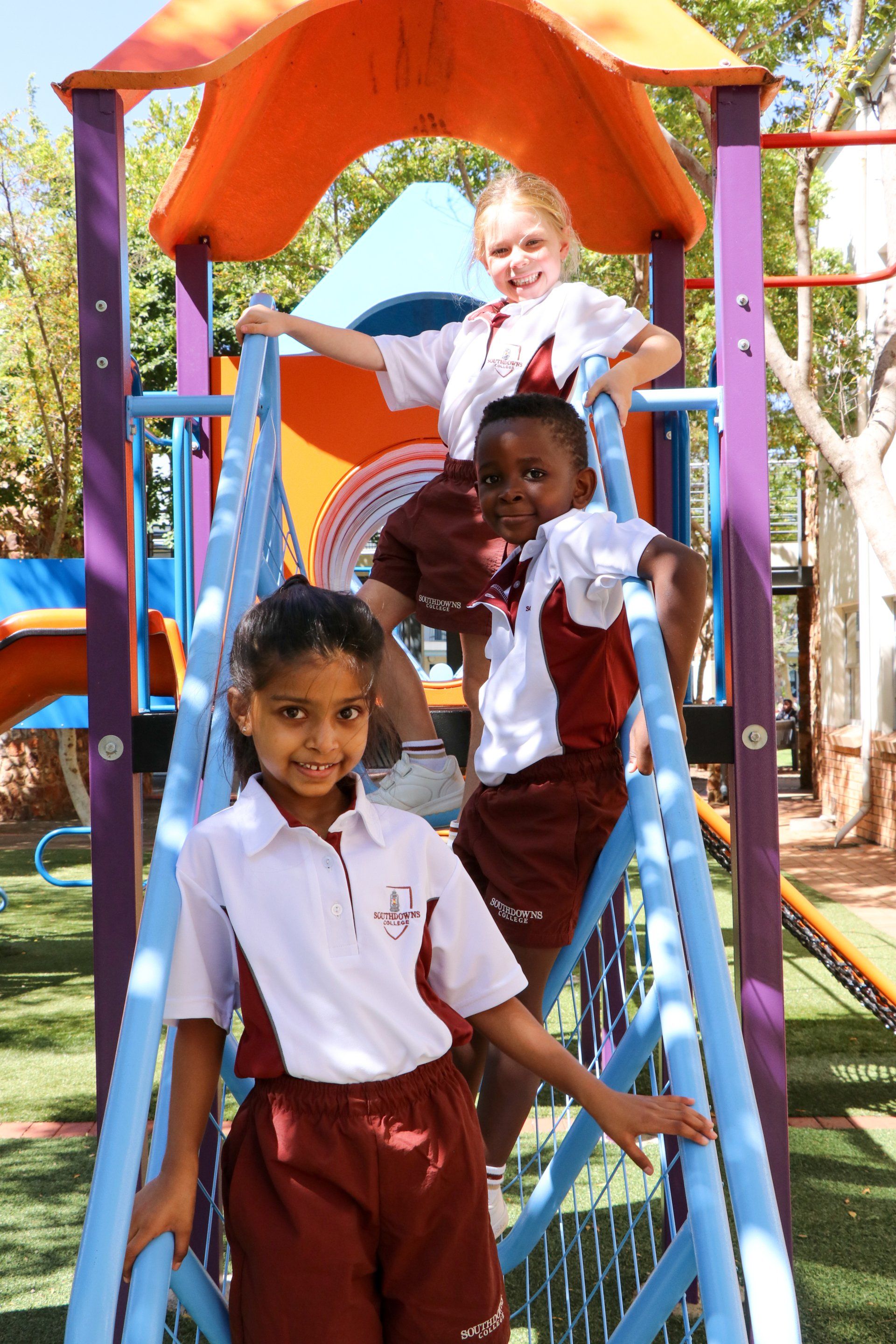 Three children are playing on a slide at a playground