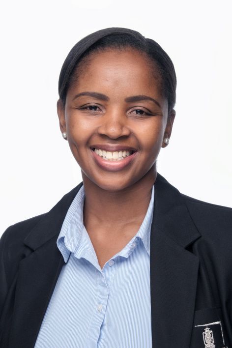 A woman wearing a black jacket and a blue shirt is smiling