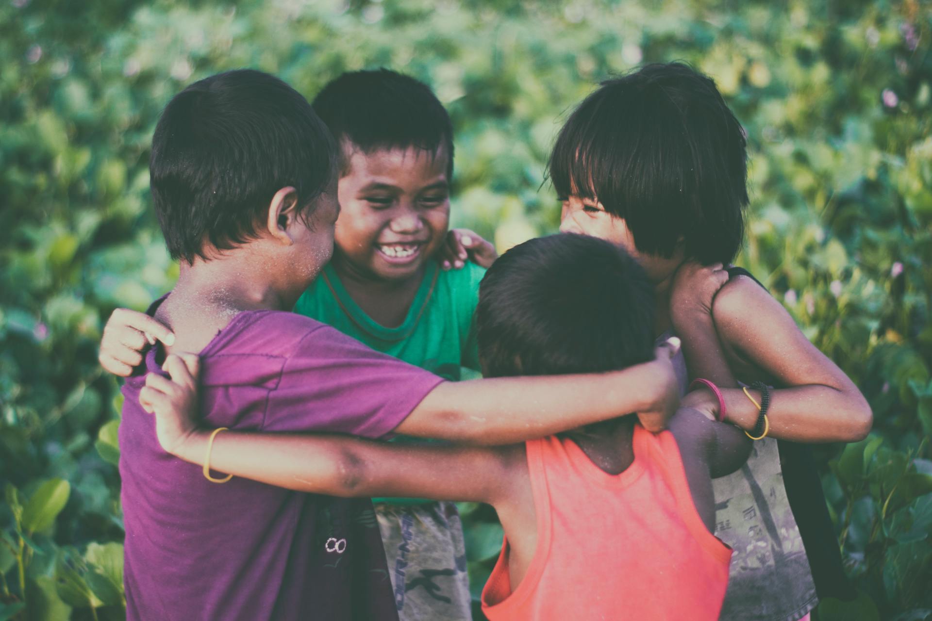 A group of children are hugging each other in a circle.