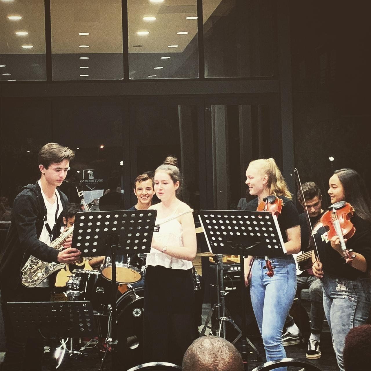 A group of young people playing musical instruments on stage