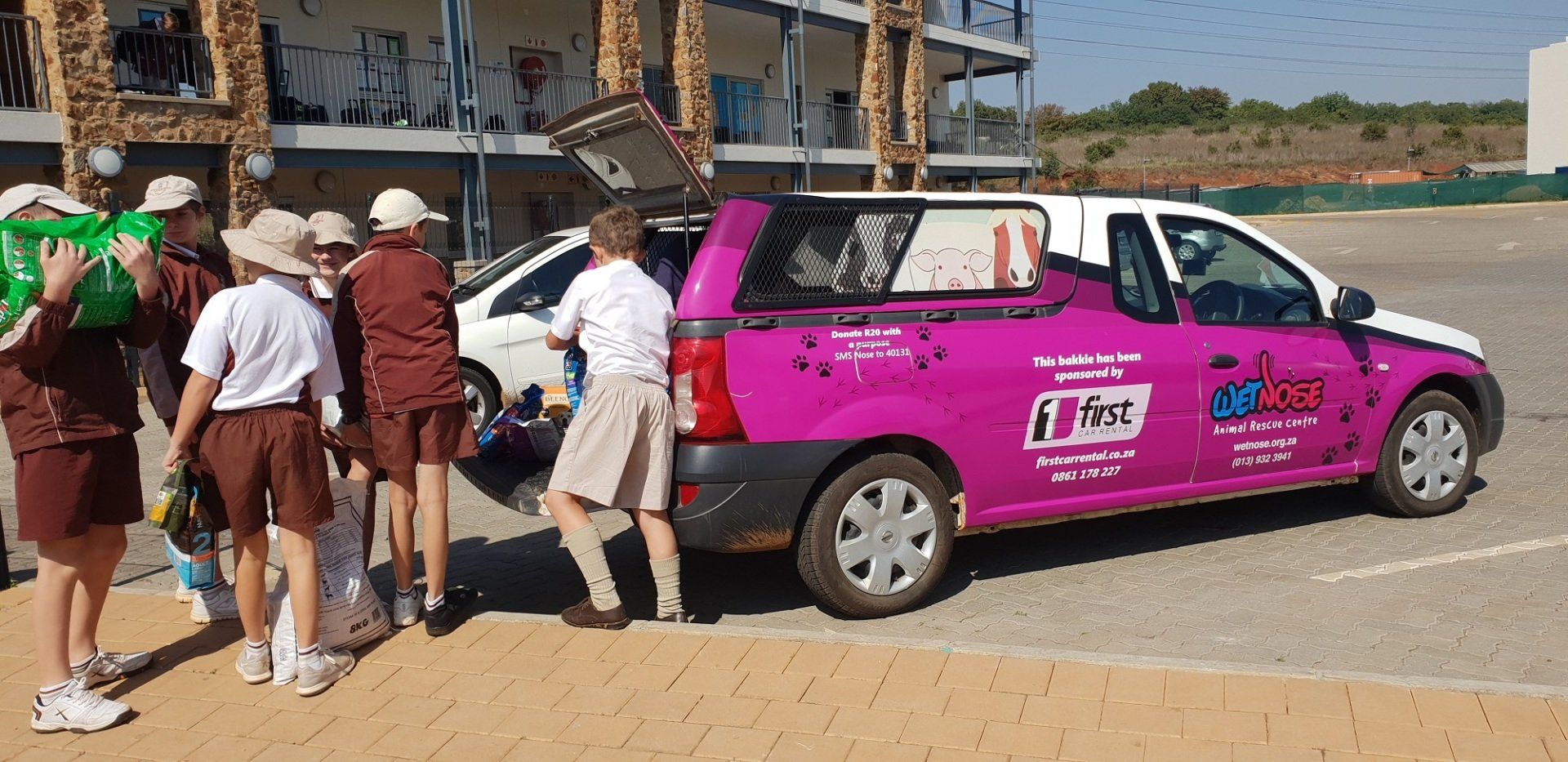 A group of people are standing around a purple and white van.