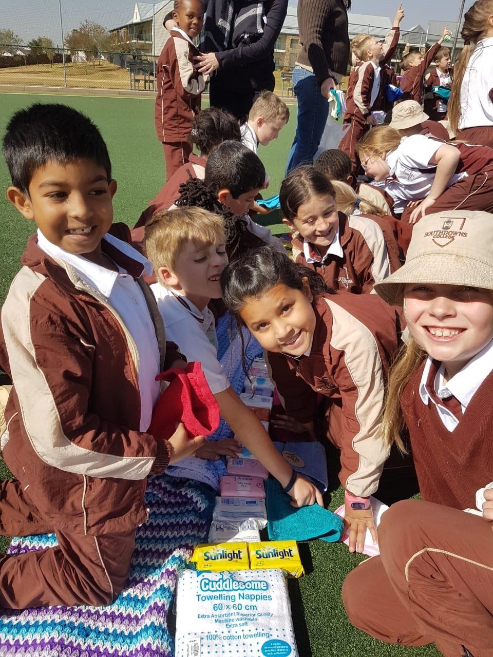 A group of children in school uniforms are sitting on the grass.