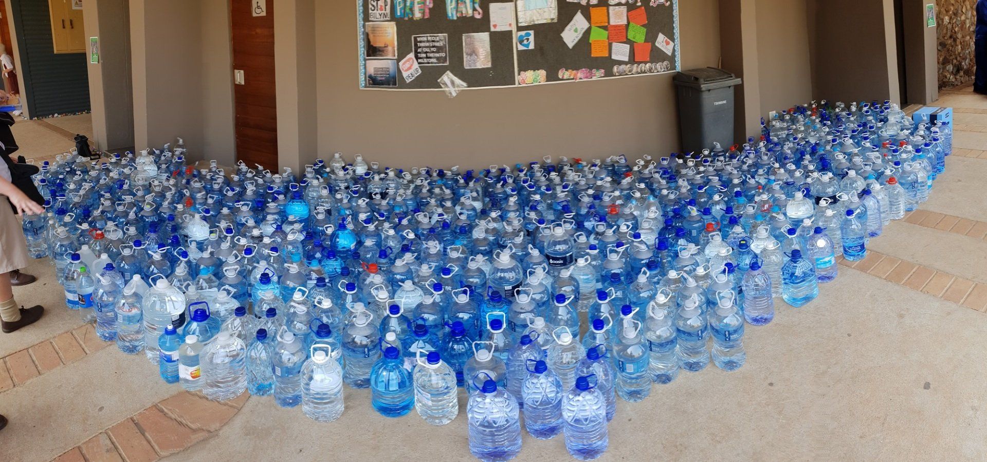 A bunch of water bottles are sitting on the floor in a room.
