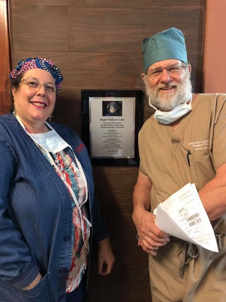 A man and a woman are standing next to each other in front of a plaque.