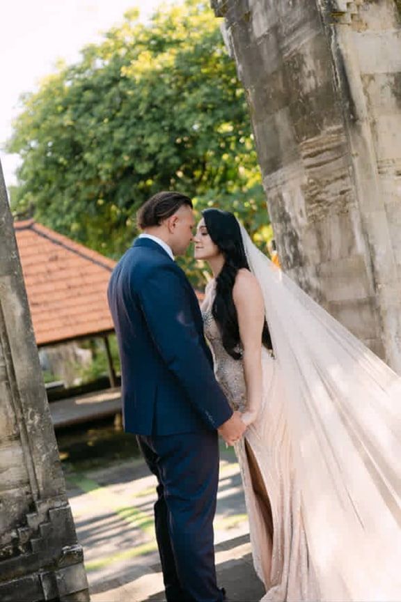 A Bride and Groom Are Kissing in Front of a Stone Wall — Eternal Weddings & Couture In Woolner, NT