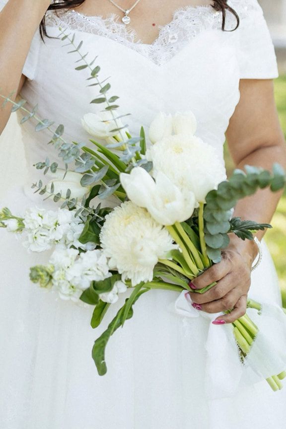 A Woman in a White Dress is Holding a Bouquet of White Flowers — Eternal Weddings & Couture In Woolner, NT