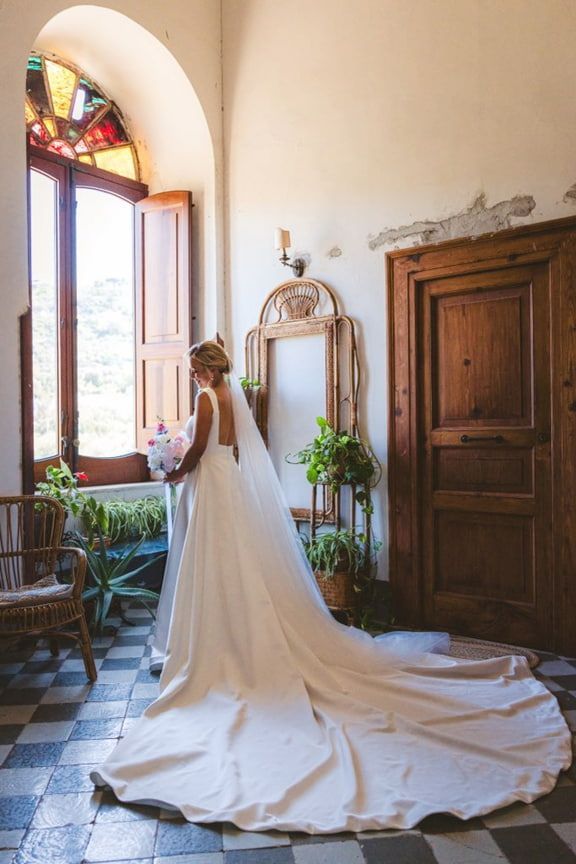 A Bride in a Long Wedding Dress is Standing in Front of a Window — Eternal Weddings & Couture In Woolner, NT