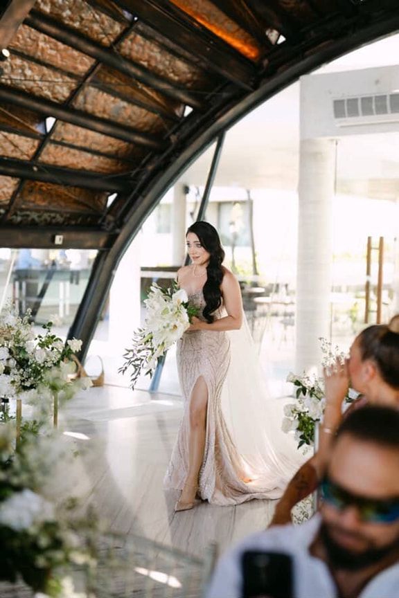 A Bride is Walking Down the Aisle at Her Wedding Holding a Bouquet of Flowers — Eternal Weddings & Couture In Woolner, NT