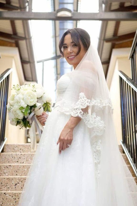 A Bride in a Wedding Dress And Stairs Holding a Bouquet of Flowers — Eternal Weddings & Couture In Woolner, NT