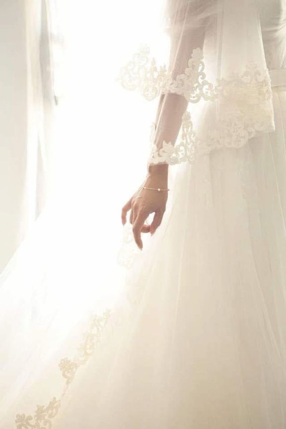 A Bride in a White Wedding Dress is Standing in Front of a Window — Eternal Weddings & Couture In Woolner, NT