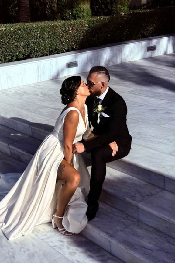 A Bride and Groom Are Kissing While Sitting on a Set of Stairs — Eternal Weddings & Couture In Woolner, NT