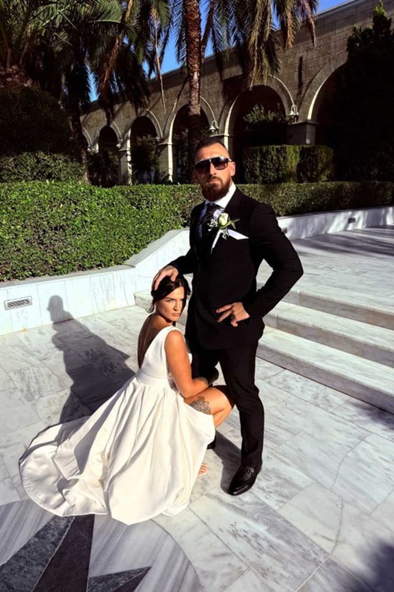 A Bride and Groom Are Posing for a Picture in Front of a Building — Eternal Weddings & Couture In Woolner, NT