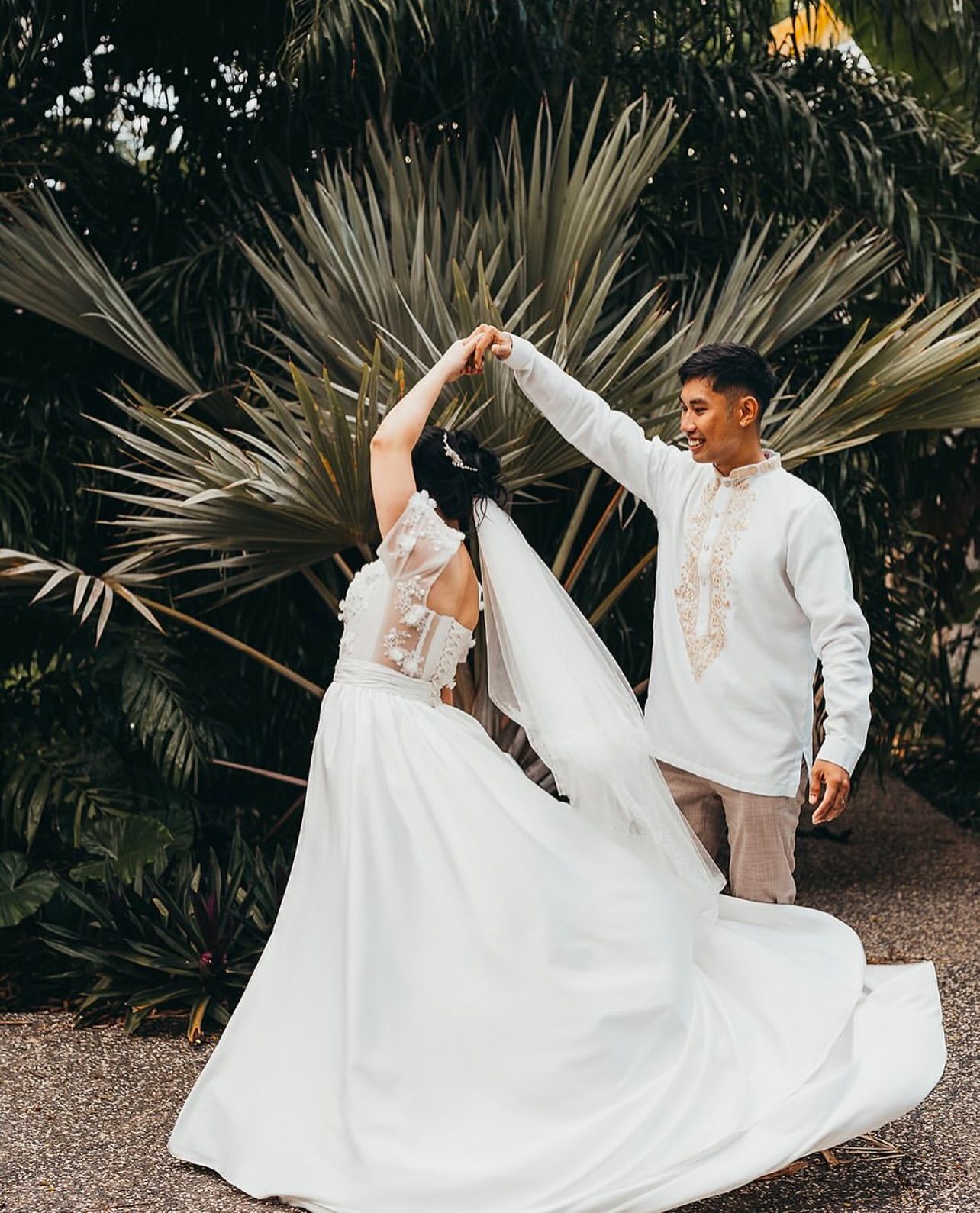 A bride and groom are dancing in front of a palm tree — Eternal Weddings & Couture In Woolner, NT