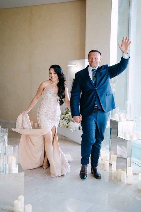 A Bride and Groom Are Walking Down a Aisle Holding Hands — Eternal Weddings & Couture In Woolner, NT