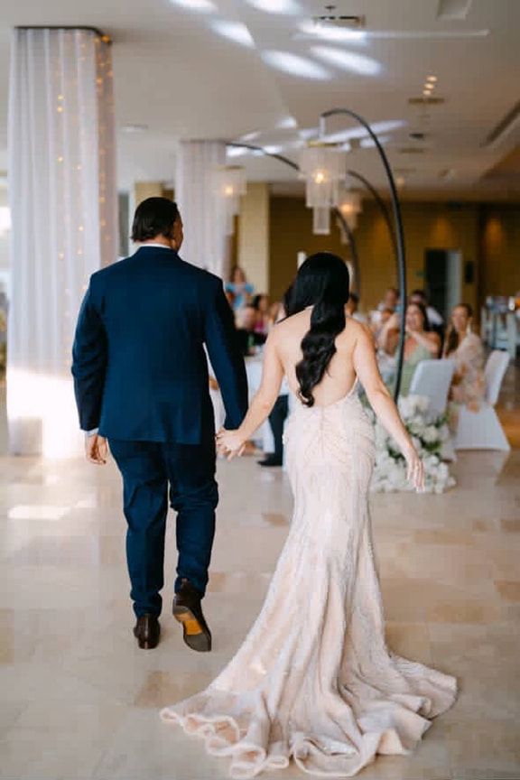A Bride and Groom Are Walking Down the Aisle at Their Wedding Holding Hands — Eternal Weddings & Couture In Woolner, NT