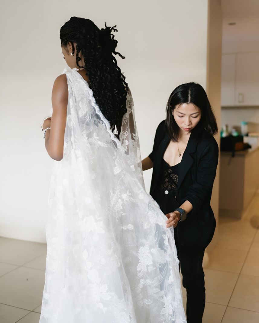 A Woman Is Helping A Woman With Her Wedding Dress — Eternal Weddings & Couture In Woolner, NT