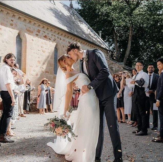 A Bride And Groom Kissing In Front Of A Church — Eternal Weddings & Couture In Woolner, NT
