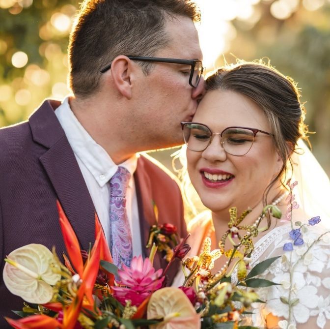A Man Kissing A Woman On The Forehead While Holding A Bouquet Of Flowers — Eternal Weddings & Couture In Woolner, NT