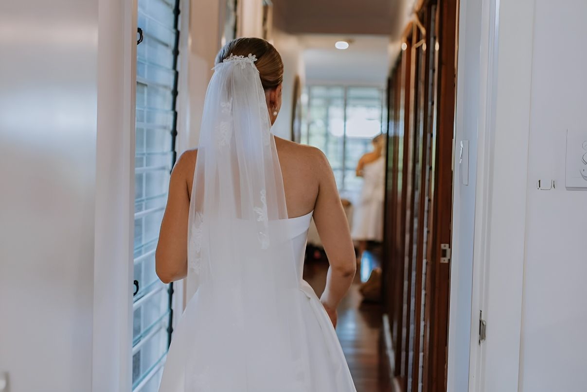 A Bride In A Wedding Dress And Veil Is Walking Down A Hallway — Eternal Weddings & Couture In Woolner, NT