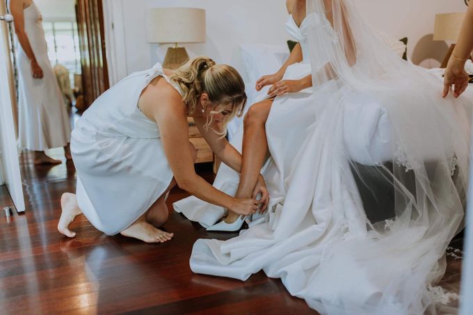 A Woman Is Helping A Bride Put On Her Wedding Shoes — Eternal Weddings & Couture In Woolner, NT