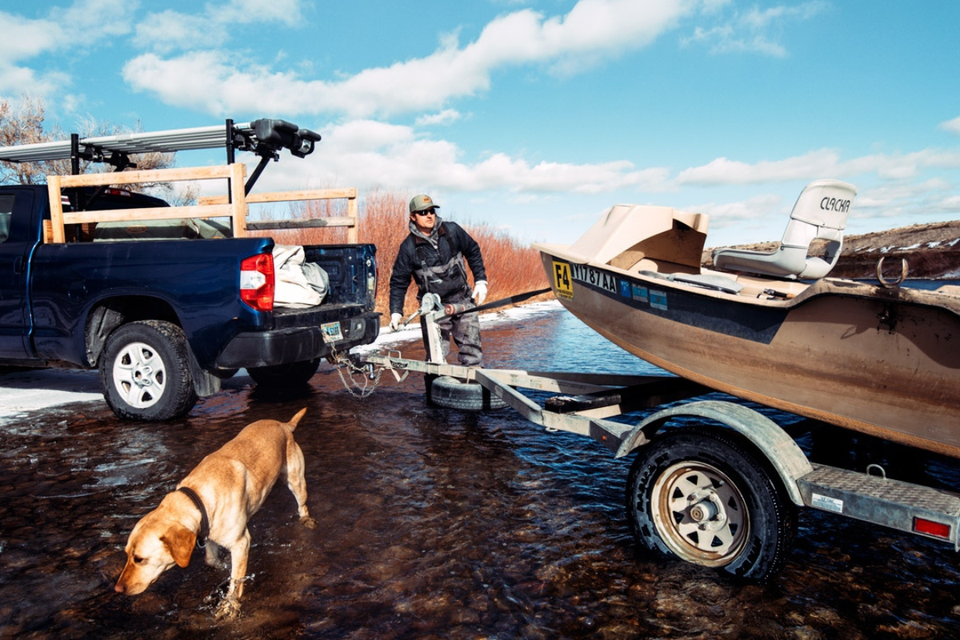 A man is pulling a boat on a trailer.