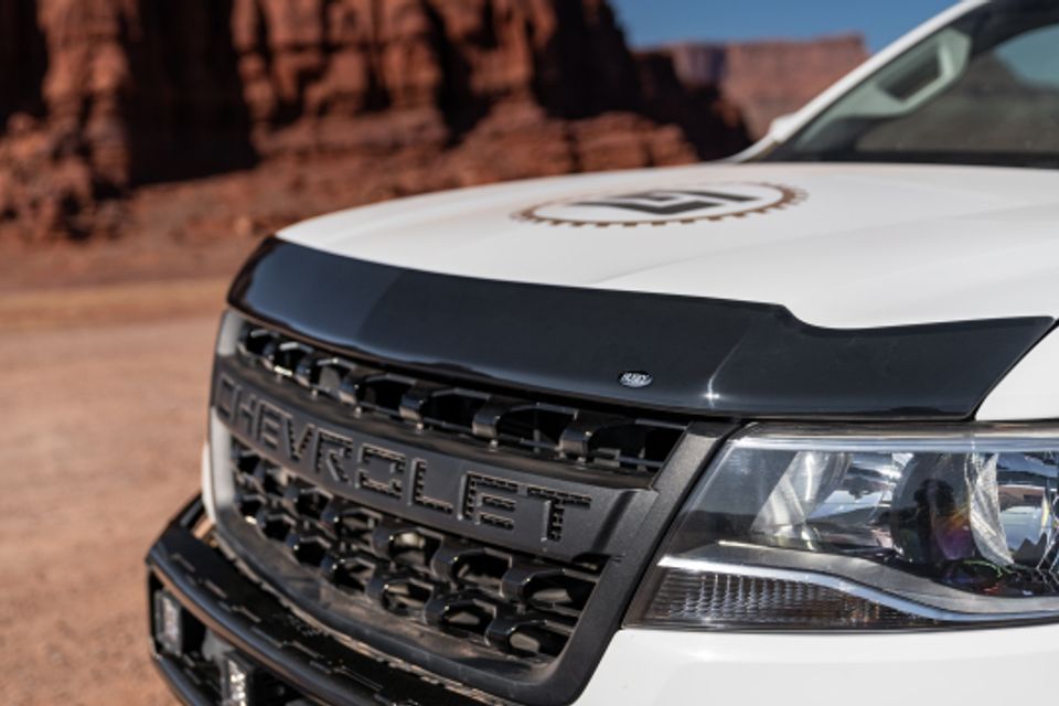 A white chevrolet truck is parked in the desert.